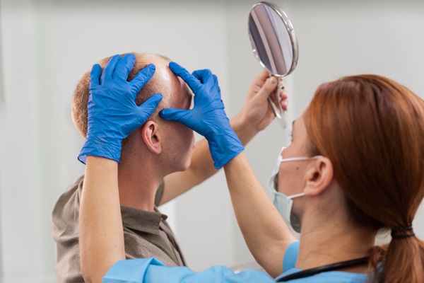 Injerto capilar España - Médico tricólogo evaluando el cuero cabelludo de un hombre con alopecia para determinar la mejor técnica de implante capilar