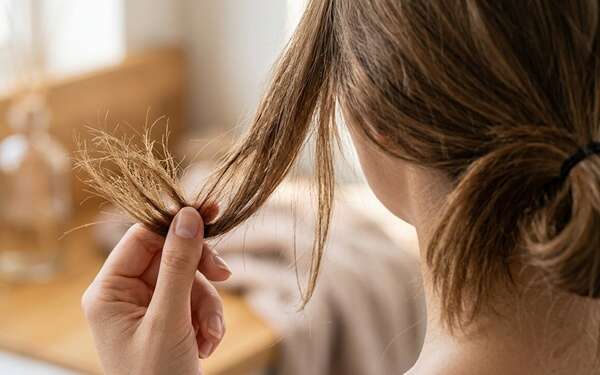 Pelo quebradizo - Mujer con el pelo quebrado en las puntas por falta de hidratación capilar