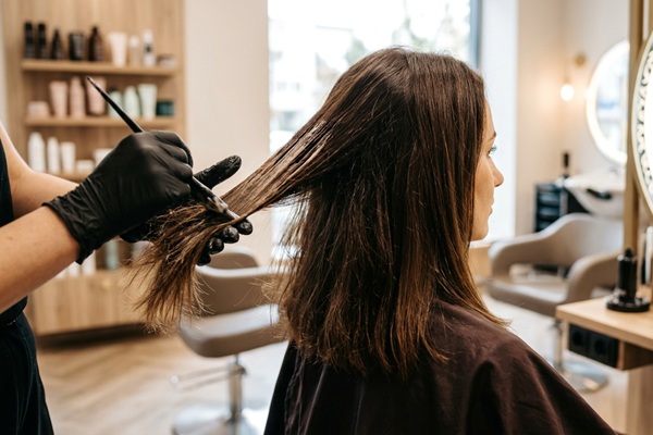 Pelo quebradizo - Estilista aplicando un tratamiento hidratante en el pelo quebrado de una mujer para nutrir la hebra capilar