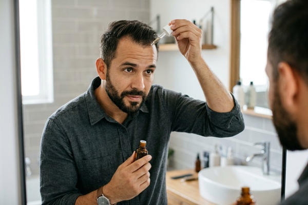 Preoperatorio injerto capilar - Hombre aplicando minoxidil en el cabello antes del injerto capilar España